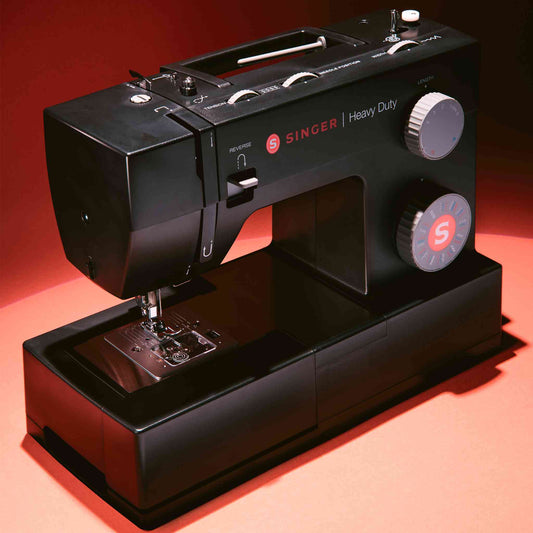 Singer 4432 sewing machine in black shown with red background on front side angle