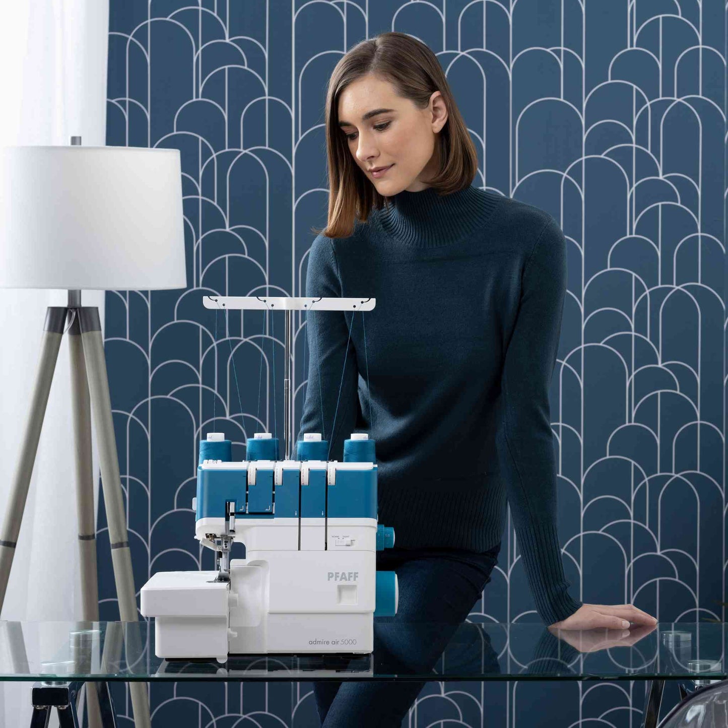 Pfaff Admire Air 5000 overlocker / serger air threading machine shown with a model in front of blue and grey geometric wallpaper.